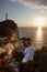 man with drone at the cliff near sea sunset above the lighthouse