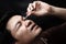 Man dropping eye drop medicine healing his eye pain with black background