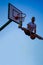 Man dunking in a basket over blue sky