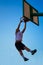 Man dunking in a basket over blue sky