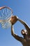 Man Dunking Basketball Into Hoop Against Blue Sky