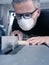 Man with a dust mask and goggles working on a circular saw