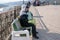 A man earns money playing the accordion, sitting on a bench on the observation deck over the Yenisei river