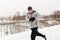 Man with earphones running along winter bridge