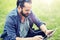 Man with earphones and tablet pc sitting on grass