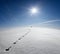 Man, Earth, Universe. Lonely Man Walking On Snow Crust Field On The Trail Of Hare At The Background Of The Sun And Flying Plane. A