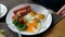 Man eating breakfast. Knife and fork in hand. American style breakfast with fried eggs, sausage, salad and toast.