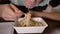 Man eating chinese noodles from a white plastic container