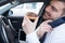 Man eating a doughnut and talking on the phone driving car