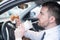 Man eating an hamburger and driving seated in car