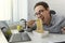 man eating instant noodles while working with laptop in office