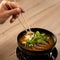 Man Eating Meat thai soup with chopsticks. Close up shot. Bowl of hot soup with onion and parsley for lunch. Spicy