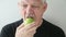 Man eats green apple front view