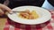 A man eats Italian pasta with chicken meatballs and tomato sauce.