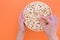 Man eats popcorn from a paper cup. Hands hold a cup with popcorn and take it on an orange background