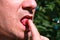 Man eats raspberries, mouth close up outdoor.