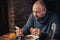 A man eats a sandwich and looks at the phone at home. Ordinary middle-aged man. Eating with a phone in hand