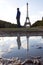 Man a the Eiffel tower reflected in a puddle