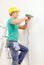 Man with electric drill making hole in wall