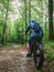 A man on an electric fatbike rides through a wet forest.