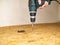 A man with a electric screwdriver tightens self-tapping screw into wood.