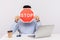 Man employee sitting in office workplace with laptop, hiding face behind stop symbol, warning with red traffic sign