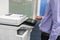 Man employee work with multifunction printer to scan and copy business documents in office