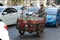 Man with empty soft drink bottles in his motorized cart on busy street