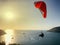 A man is engaged in paragliding. Red Parachute in the blue sky against the background of yacht