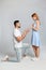 Man with engagement ring making marriage proposal to girlfriend on grey background