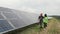 Man engineer specialist and female electrical worker walking on photovoltaic solar panels and discussing future plans