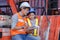 Man engineering and daughters sitting on forklift working with clipboard in container yard.