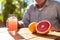 man enjoying glass of grapefruit juice on a sunny patio