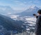 Man enjoys the view and looks down on Garmisch-Partenkirchen and Farchant and takes pictures with his smartphone