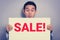 A man with excited face showing SALE! sign