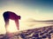 Man exercising on beach. Silhouette of active man exercising and stretching at lake