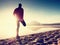 Man exercising on beach. Silhouette of active man exercising and stretching at lake