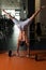 Man Exercising Handstand Push-Ups On Barbell In Gym