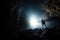 A man explore a deep cave with light ray from above. Outdoor adventure concept.