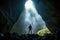 A man explore a deep cave with light ray from above. Outdoor adventure concept.