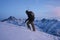 Man explorer with a snowboard behind his back climb on high mountain