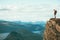 Man explorer standing on cliff alone mountain summit