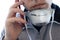 A man in a facial respiratory mask makes a phone call. Respirator on the neck. Man face close-up. Virus or disease alert concept