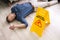 Man Falling On Wet Floor In Front Of Caution Sign