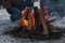 Man is fan campfire bright flames in a wild at the dusk, closeup winter camping bonfire at night, front selective focus