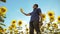 Man farmer in a plaid shirt working holding in hand a plastic bottle sunflower oil stands in the field . slow motion