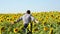 A man-farmer runs across the sunflower field in slow motion