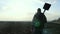 Man farmer silhouette red neck holding a shovel in his hand walking across the field a pile of dirt soil. Eco smart