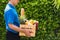 Man farmer wears delivery uniform he holding full fresh vegetables and fruits in crate wood box