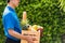 Man farmer wears delivery uniform he holding full fresh vegetables and fruits in crate wood box